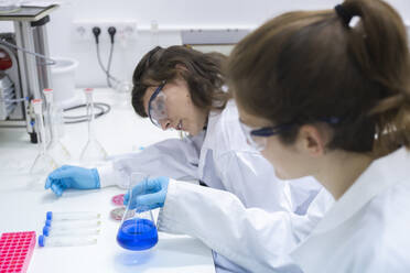 Wissenschaftler bei der Untersuchung einer blauen Chemikalie in einem Kolben im Labor - PCLF00038