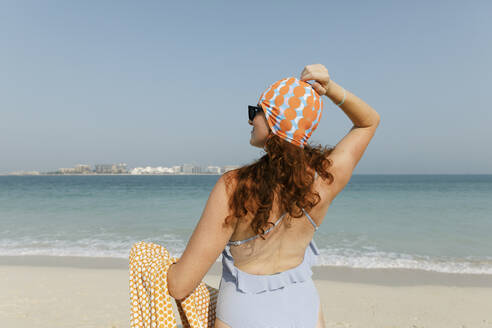 Woman wearing swimsuit enjoying sunny day at beach - TYF00436
