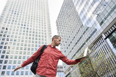 Freelancer with laptop in front of modern buildings - VEGF05970