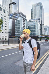 Mann mit Rucksack trinkt Kaffee auf der Straße in der Stadt - VEGF05993