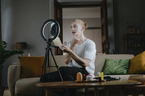 Young influencer applying make-up and vlogging in front of mobile phone at home - YTF00187