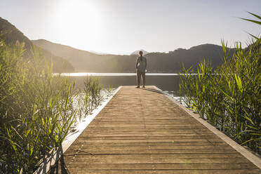 Woman standing on jetty over lake at vacation - UUF27412