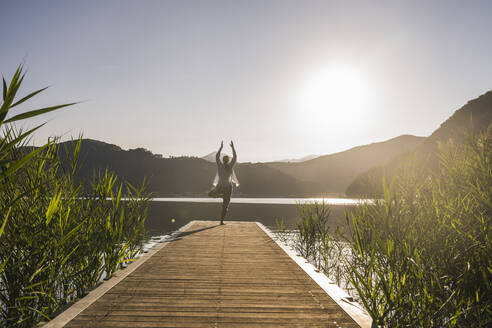 Woman balancing on one leg and practicing yoga at vacation - UUF27417