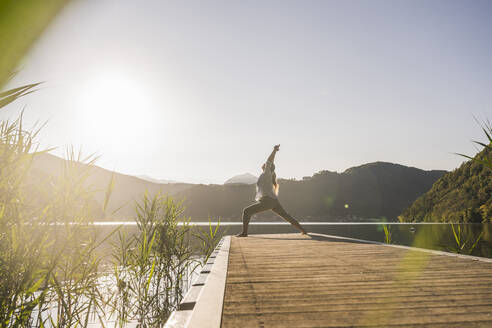 Woman stretching hands on jetty by lake and mountains at vacation - UUF27422