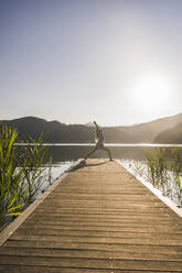 Frau übt Yoga auf dem Steg über dem See - UUF27423