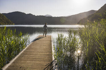 Ältere Frau bewundert den See auf dem Steg stehend - UUF27433