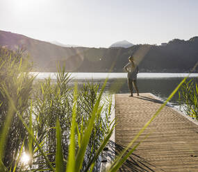 Mature woman admiring lake on jetty at vacation - UUF27434