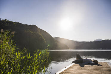 Reife Frau ruht sich auf dem Steg über dem See im Urlaub aus - UUF27441