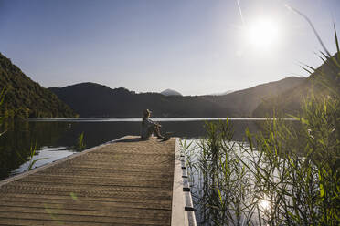 Reife Frau mit Laptop mit Blick auf den See und die Berge - UUF27446