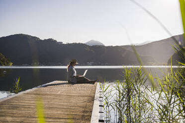 Frau arbeitet am Laptop am See - UUF27447