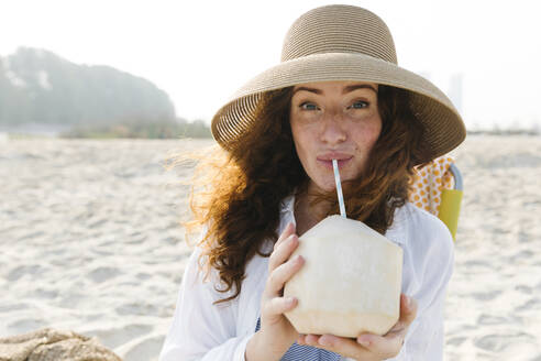 Frau trinkt Kokosnusswasser am Strand - TYF00442