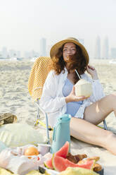 Glückliche Frau mit Kokosnuss genießt sonnigen Tag am Strand - TYF00443