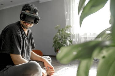 Lächelnder Mann trägt Virtual-Reality-Simulator zu Hause - ANAF00078