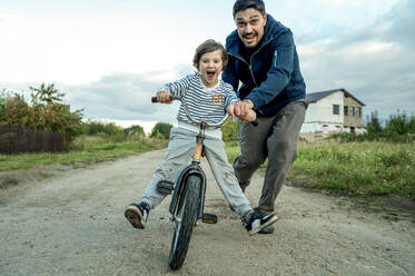 Vater bringt seinem Sohn das Fahrradfahren auf der Straße bei - ANAF00089