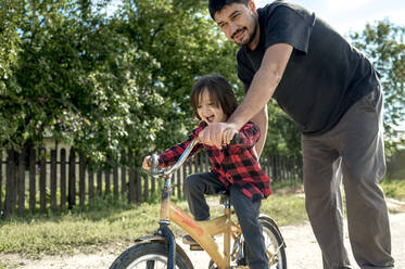 Man pushing son on bicycle - ANAF00093