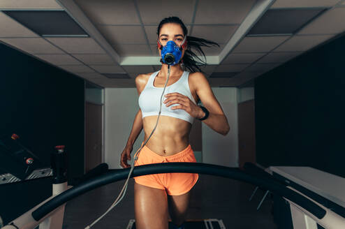 VO2-Max-Test: Sportlerin mit Maske beim Laufen auf dem Laufband. Sportlerin im sportwissenschaftlichen Labor bei der Messung ihrer VO2-Max. - JLPSF02461