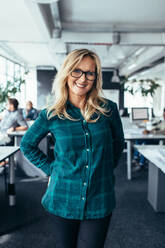 Vertical shot of mature female standing in office. Caucasian woman standing in creative work place. - JLPSF02509