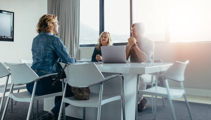 Woman sitting in a conference room for a job interview situation. Authentic image in modern office space. - JLPSF02523