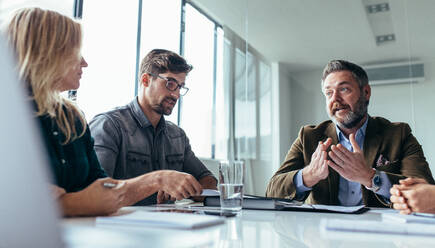 Team of business professionals having a meeting in conference room. Businessman explaining project to colleagues. - JLPSF02536