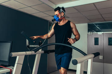 Performance testing. Runner with mask on treadmill in sports science laboratory. Athlete walking on a treadmill and measuring his performance and oxygen consumption. - JLPSF02622