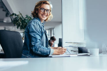 Female manager working at her desk. Smiling businesswoman sitting in office. - JLPSF02666