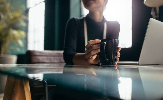 Weibliche Hand hält Tasse Kaffee, Kaffeetasse auf Tisch mit Frau. - JLPSF02729