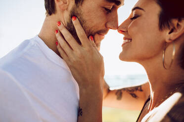 Close up of romantic young couple together outdoors. Loving man and woman caught in a romantic moment. - JLPSF02764