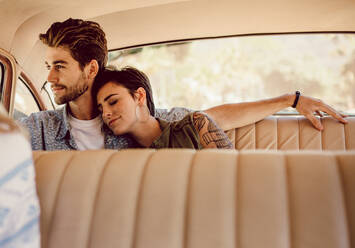 Junger Mann und Frau sitzen auf der Rückbank eines Autos, ein Paar reist mit einem alten Auto. - JLPSF02783
