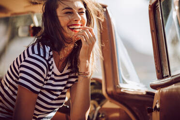 Beautiful woman sitting in a car and laughing. Woman having fun outdoors on the road trip. - JLPSF02799