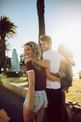 Group of three young friends looking back and smiling while walking in the park. Young man and women enjoying a summer day at park. - JLPSF02810