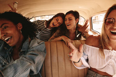 Young female friends on a road trip traveling by a car and having a great time. Group of women enjoying car ride. - JLPSF02830