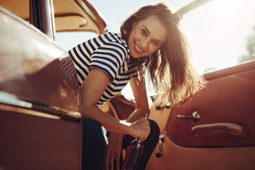 Porträt einer fröhlichen Frau, die sich im Auto entspannt und in die Kamera schaut, auf einer Sommerreise. - JLPSF02841