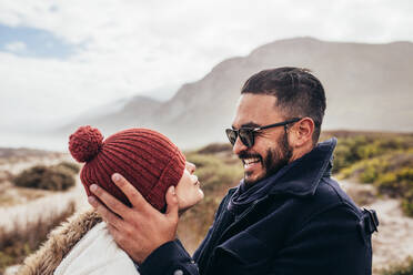 Close up portrait of loving couple in warm clothing outdoors. Side view of smiling man and woman enjoying a winter day at the beach. - JLPSF02952
