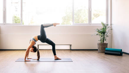 Fitness-Frau macht Backbend Stretching Yoga-Übung. Gesunde Frau übt Yoga, einbeinige Rad-Pose. - JLPSF02959