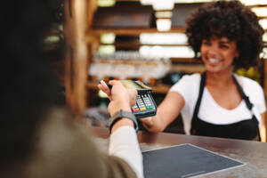 Kassierer, der Zahlungen über NFC-Technologie annimmt. Kunde, der drahtlos oder kontaktlos mit Kreditkarte bezahlt. - JLPSF02967