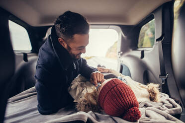 Young man and woman in love lying in car trunk and smiling. Romantic young couple resting in car trunk. - JLPSF02975