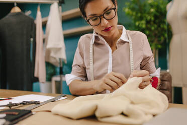 Näherin, die ein Designerkleid näht. Eine Schneiderin fertigt in ihrem Atelier ein Kleid an. - JLPSF03015