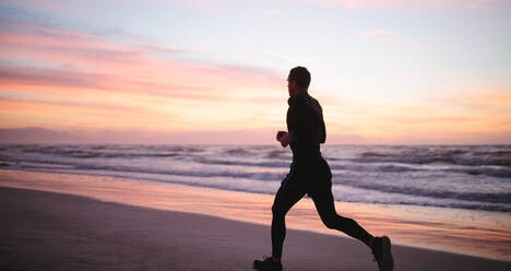 Ein Mann, der am Morgen am Strand joggt. Ein gesunder Mann joggt am Meer. - JLPSF03017