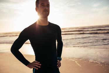 Porträt eines selbstbewussten männlichen Sportlers, der am Strand steht. Mann in Sportkleidung am Morgen am Meer. - JLPSF03031