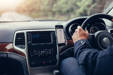 Mann fährt Auto mit mobilem Navigationssystem. Männlich mit Handy mit Karte gps Navigation im Auto. - JLPSF03049
