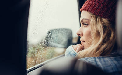 Beautiful young female sitting on a car and looking outside the window. Thoughtful female travelling by a car. - JLPSF03051