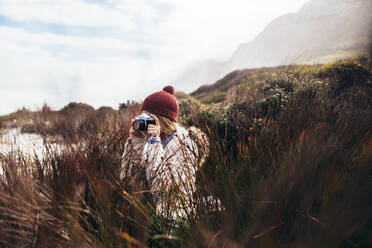 Junge Frau steht im Freien und fotografiert die Natur mit einer Digitalkamera. Fotografin macht Reise-Naturfotografie. - JLPSF03077