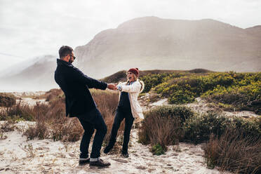 Happy couple in warm clothing enjoying vacation. Loving couple having fun at the beach on winter day. - JLPSF03088