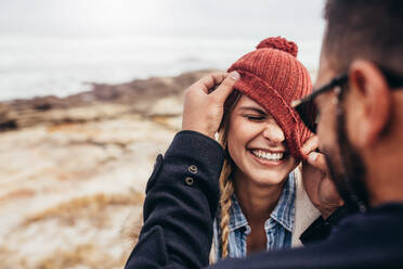 Nahaufnahme eines lächelnden jungen Paares, das sich an einem Wintertag am Strand vergnügt: Mann und Frau. - JLPSF03094