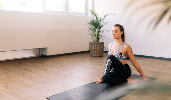 Gesunde Frau sitzt auf Übungsmatte und macht Yoga. Kaukasische Frau übt Yoga für eine gute Gesundheit. - JLPSF03109