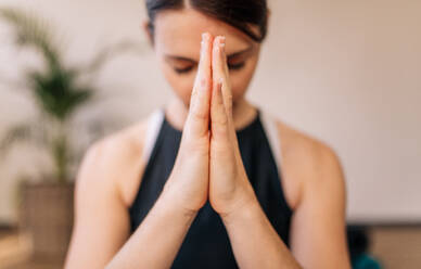 Close up of woman hands joined. Female meditating with her hands joined indoors. Namaste yoga pose, meditating, breathing and relaxing. - JLPSF03144