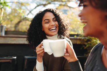 Zwei Frauen lachen und amüsieren sich in einem Café, Freunde unterhalten sich beim Kaffeetrinken. - JLPSF03177