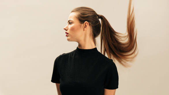 Side portrait of beautiful young brunette over beige background. Female fashion model with long hair. - JLPSF03275