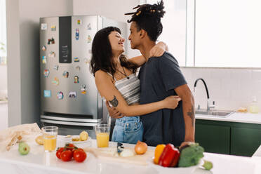 Young couple sharing a romantic moment together at home. Shot of a romantic young couple smiling cheerfully while dancing together in the kitchen. Couple tango dancing at home. - JLPSF03287