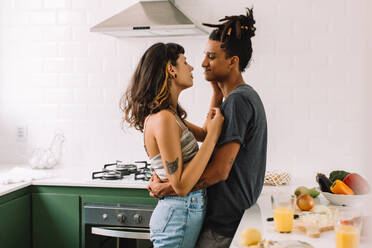 Schönes junges Paar, das sich in der Küche umarmt. Ausschnitt aus einem zärtlichen jungen Paar, das sich in der Küche umarmt. Ein Paar, das einen romantischen Moment zu Hause erlebt. - JLPSF03288